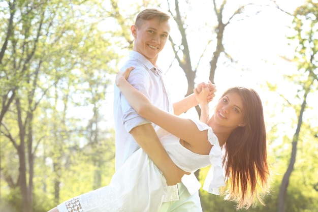 Beautiful young couple dancing in park on sunny day