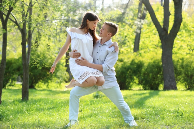 Beautiful young couple dancing in park on sunny day