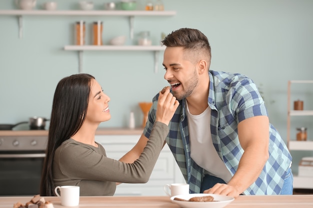 Beautiful young couple eating chocolate in kitchen