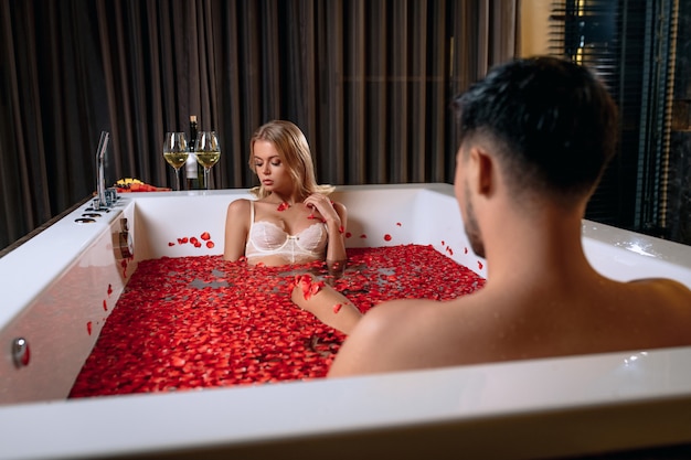 Красивая молодая пара, наслаждаясь ванну с лепестками роз