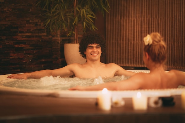 Beautiful young couple enjoying in a hot tub at the spa centre.