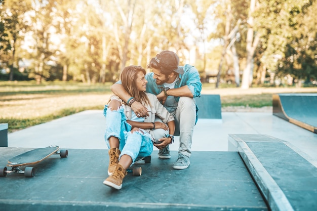 Beautiful young couple enjoying outdoors in city skateboarding park