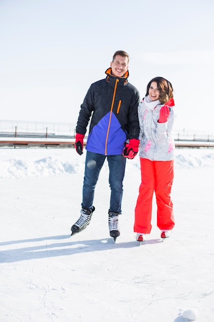 Le belle giovani coppie vanno pattinaggio su ghiaccio, vacanza attiva di stile di vita, vacanza invernale