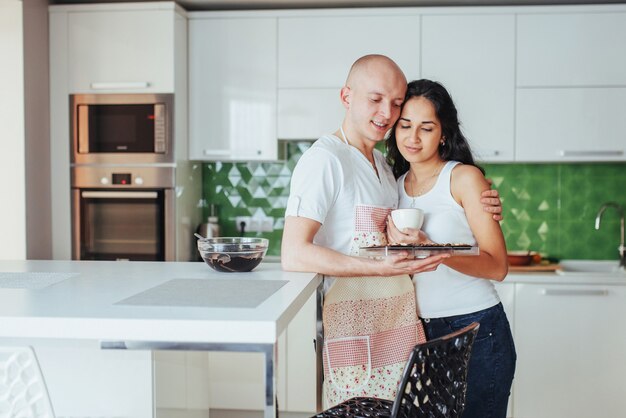 Beautiful young couple graphed smiling  while cooking in the kitchen at home.