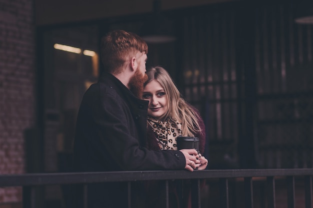 Beautiful young couple is hugging and smiling while drinking coffee in cafe