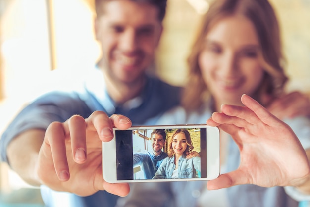 Beautiful young couple is making selfie using a smartphone.