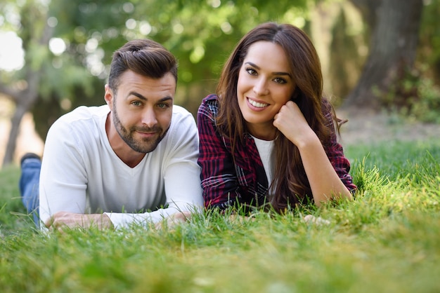 Beautiful young couple laying on grass in an urban park. 