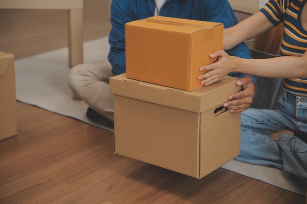 Beautiful young couple in love having fun unpacking things from cardboard boxes while moving in together in their new apartment