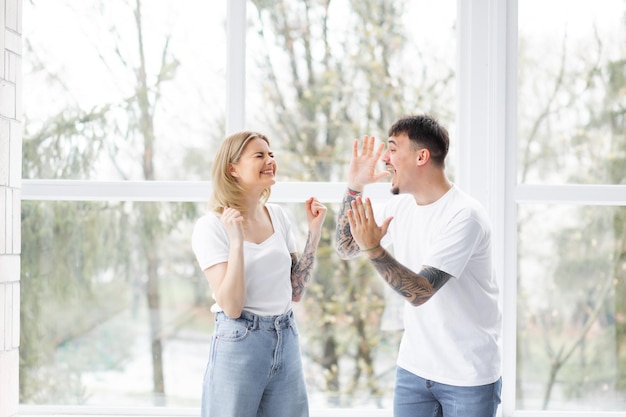 Beautiful young couple in love at home standing at the window embracing