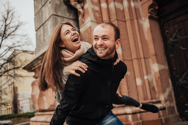 Bella giovane coppia. l'uomo trasporta sulle spalle la sua ragazza per le strade