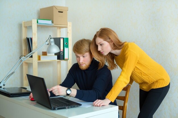 beautiful young couple man and woman working at laptop