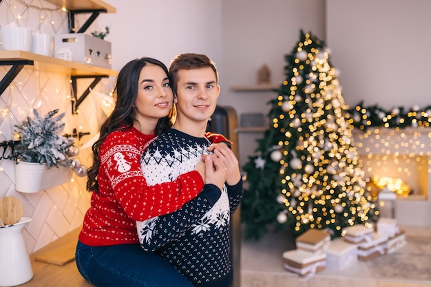 Beautiful young couple near the Christmas tree celebrating Christmas