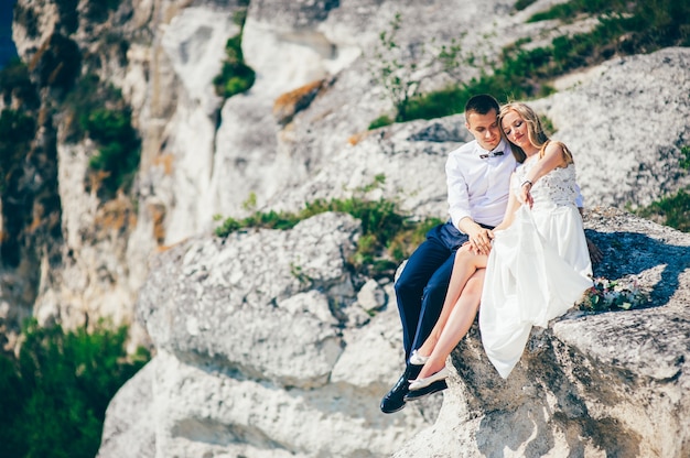 beautiful young couple posing on the rock near the lake