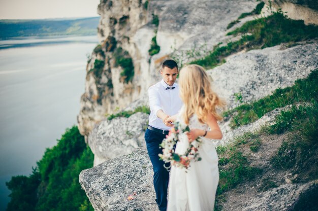 beautiful young couple posing on the rock near the lake