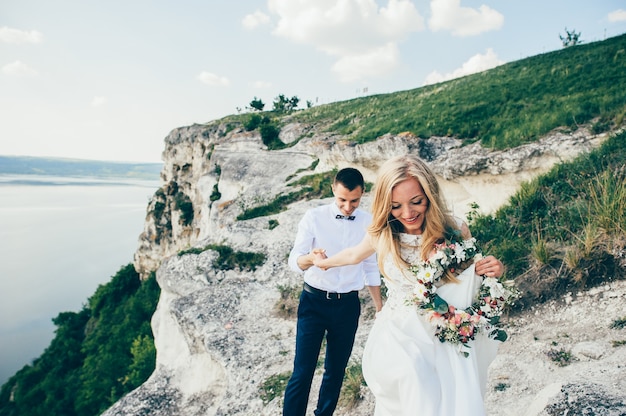 beautiful young couple posing on the rock near the lake