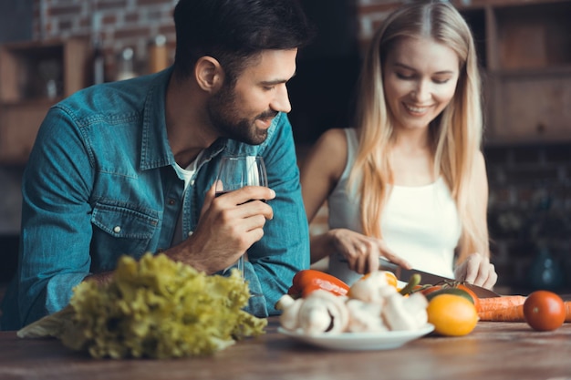 家で自由な時間を過ごしながら一緒に健康的な食事を準備する美しい若いカップル