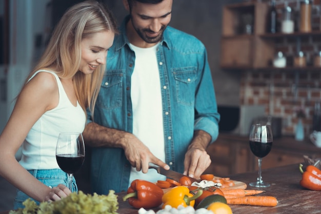 家で自由な時間を過ごしながら一緒に健康的な食事を準備する美しい若いカップル