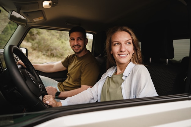 Beautiful young couple sitting on front passenger seats and driving a car