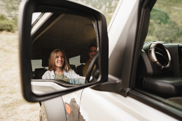 Beautiful young couple sitting on front passenger seats and driving a car