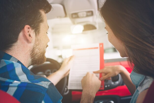 購入する車を選ぶディーラーに立っている美しい若いカップル。