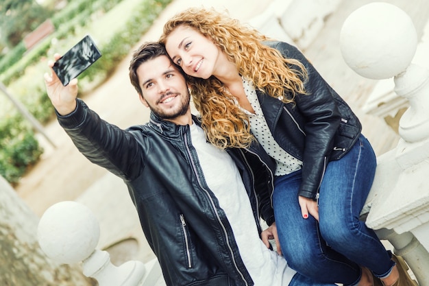 Beautiful young couple using they mobile phone in the park.