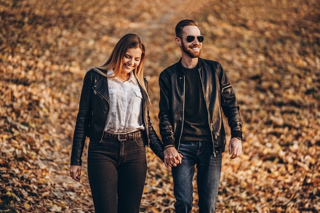 Photo beautiful young couple walking in the autumn park on a sunny day