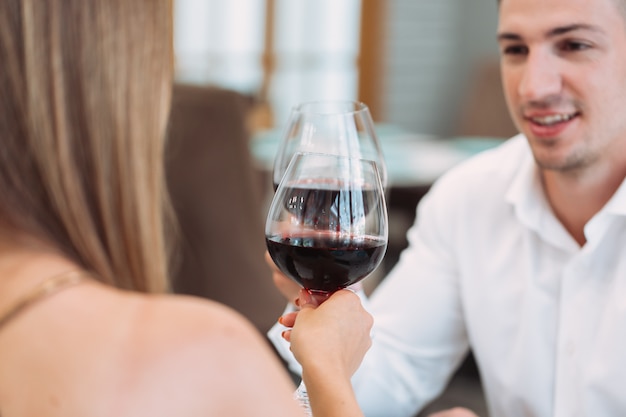 高級レストランで赤ワインのグラスと美しい若いカップル