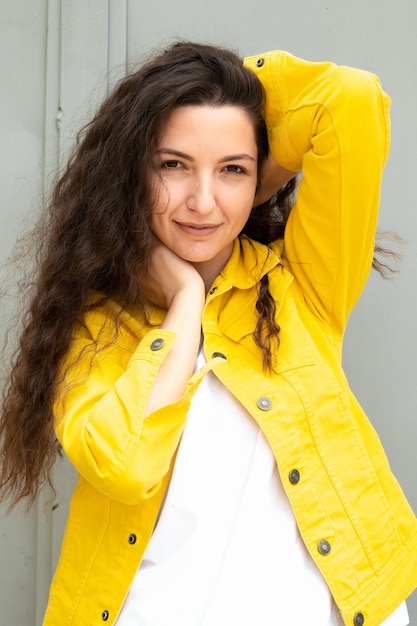 Beautiful young curly girl on a gray background.