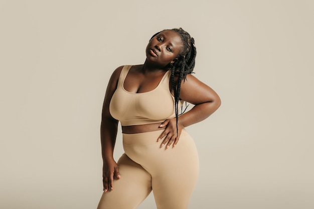 Beautiful young curvy woman in underwear looking confident in her body on studio background