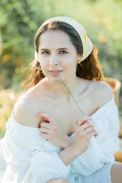 Beautiful young darkhaired woman on picnic in field Model in stylish clothes with bicycle Summer