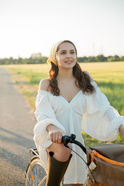 Красивая молодая темноволосая женщина на пикнике в поле Модель в стильной одежде с велосипедом Лето