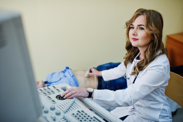 Beautiful young doctor doing diagnostic sonography on a patient