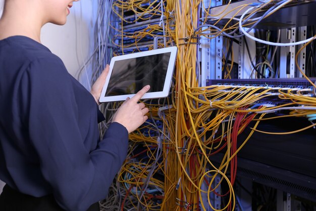 Beautiful young engineer with tablet computer in server\
room