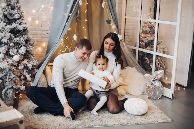 Beautiful young family under baldachin. Christmas decorations.