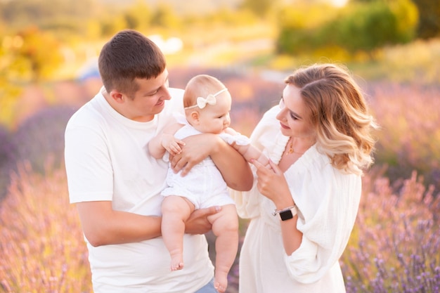 Beautiful young family, father and mother with baby on lavander field