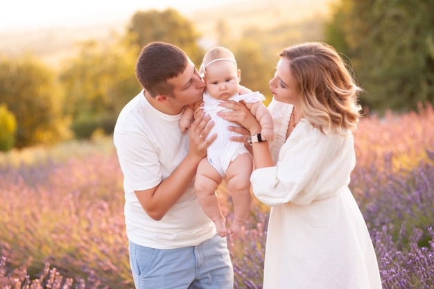 Beautiful young family, father and mother with baby on lavander field