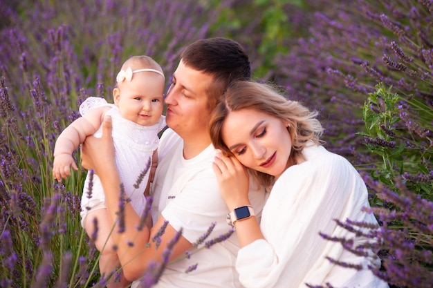 Bella giovane famiglia sul campo di lavanda fiore viola. vacanze di famiglia