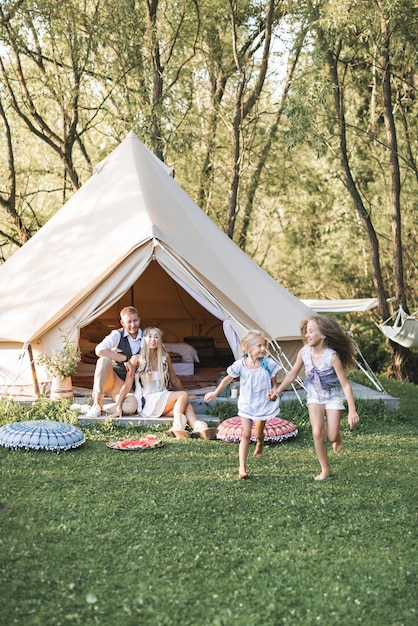 Beautiful young family spending time together in summer park or meadow