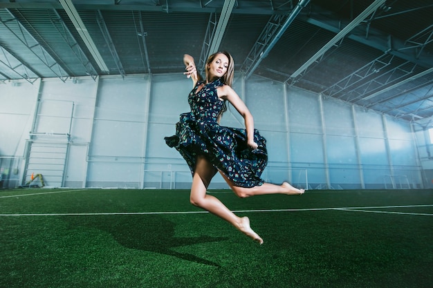 Beautiful young fashion model in a dress at a large sports stadium posing