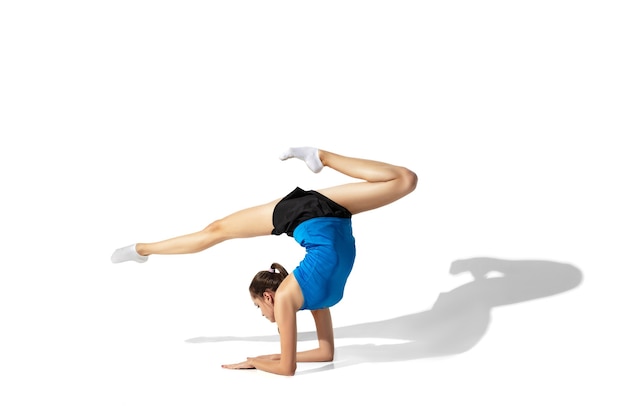 Beautiful young female athlete stretching on white with shadows