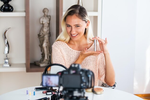 Beautiful young female blogger recording vlog video with makeup cosmetic at home online influencer on social media conceptlive streaming viral