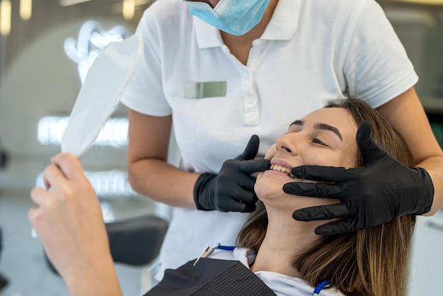 beautiful young female dentist is doing a dental examination of a girl patient in the dental office Portrait of smiling girl in dental chair in dentistry