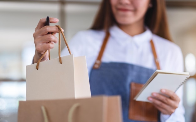 Foto una bella giovane imprenditrice con grembiule che controlla gli ordini dal cliente