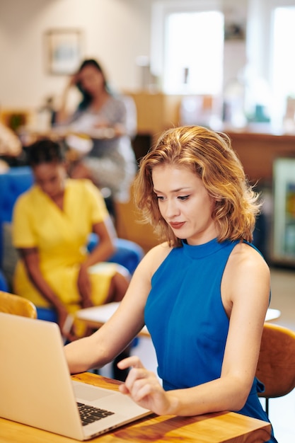 Beautiful young female entrepreneur working on laptop at table in cafe