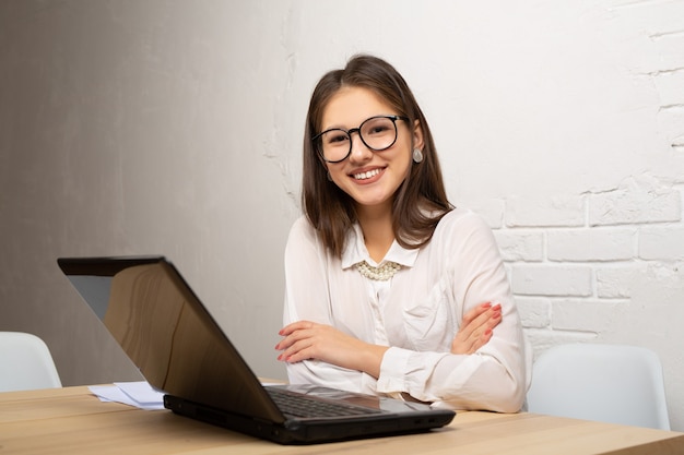 オフィスでラップトップとテーブルで眼鏡をかけて美しい若い女性