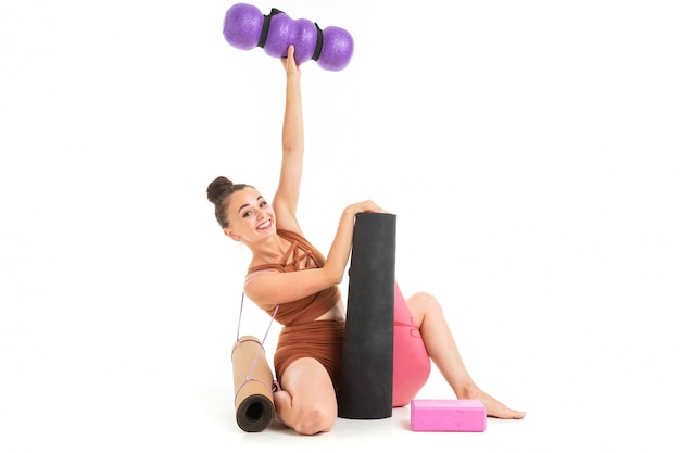 A beautiful young female gymnast sits with sporting inventory back to camera isolated on white 