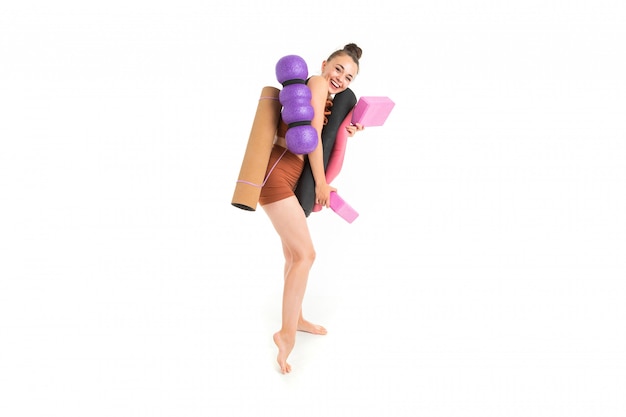 Beautiful young female gymnast with dark long hair stuffed in a bundle in brown sporting elastic suit with sporting inventory