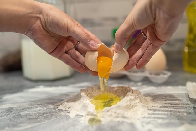 Beautiful young female hands break eggs into flour to knead a beautiful dough Cooking concept