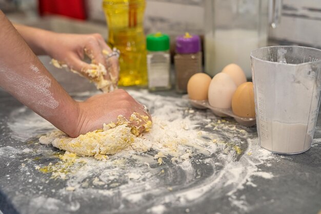 美しい若い女性の手が卵を小麦粉に砕いて美しい生地をこねる料理のコンセプト