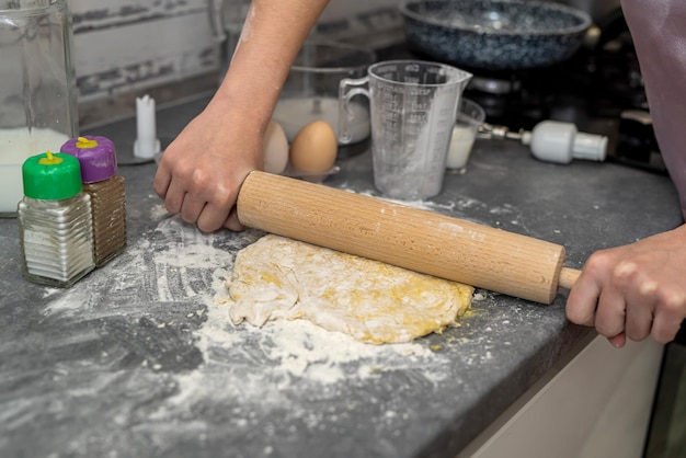 Belle giovani mani femminili rompono le uova in farina per impastare una bella pasta concetto di cottura